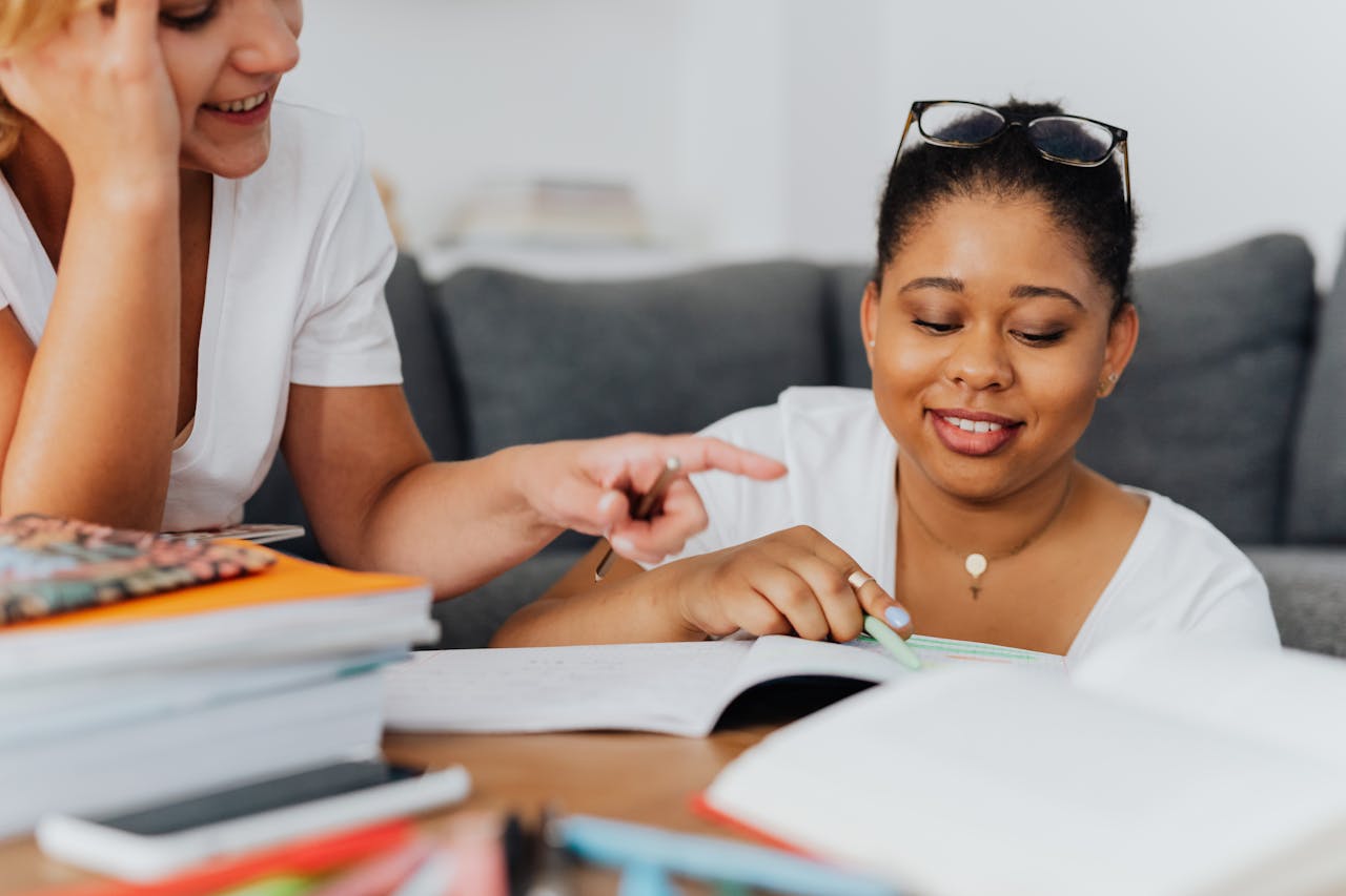 Two diverse women studying together with books in a cozy room setting.