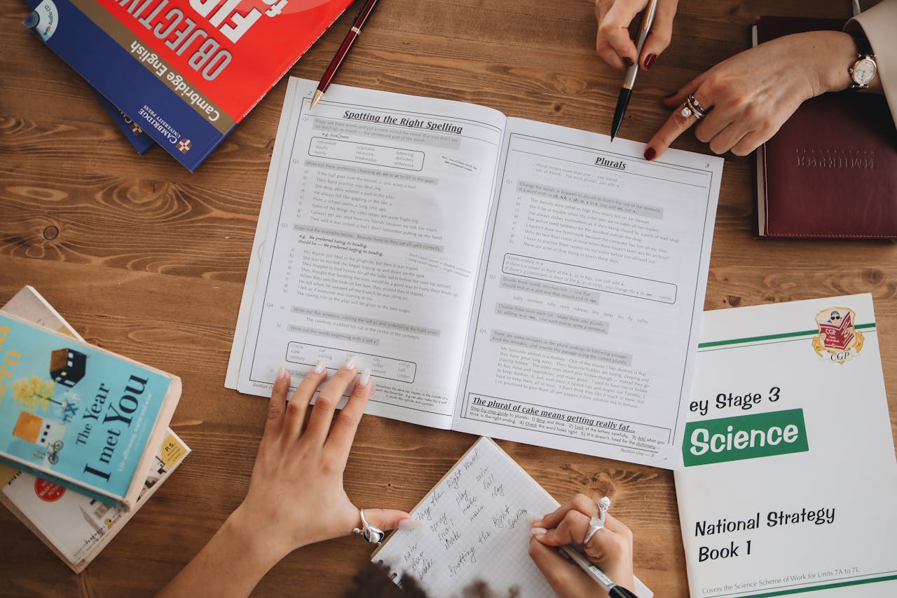 Overhead view of students studying with open books and taking notes, highlighting education and learning.